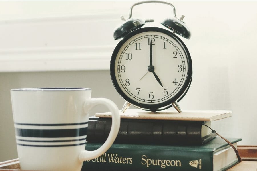 alarm clock on a stack of books with a coffee mug