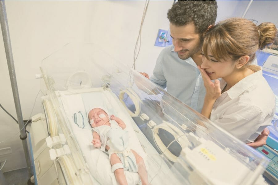 parents looking at baby in NICU crib