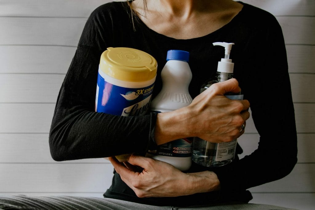 woman holding cleaning products that may contain toxins that are harmful to your health