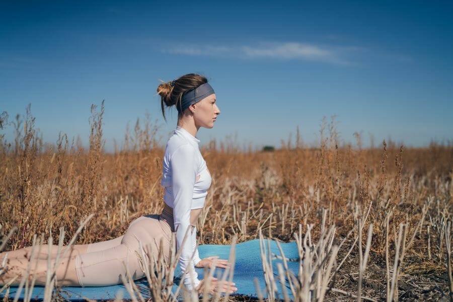 woman practicing yoga and meditation in a meadow