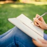woman striving for wellness enjoying fresh air outside while practicing mindfulness and journaling in the new year