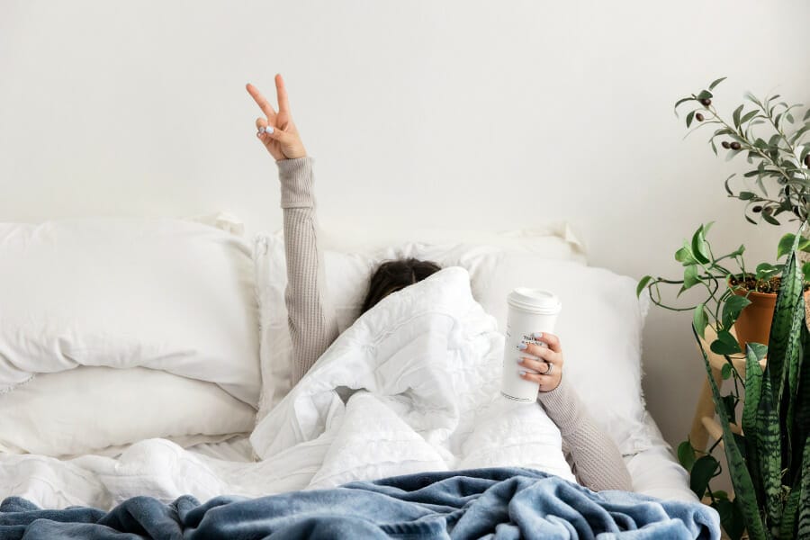 woman in bed covering face with blankets
