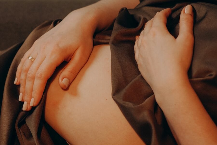 mom in postpartum period laying down holding belly