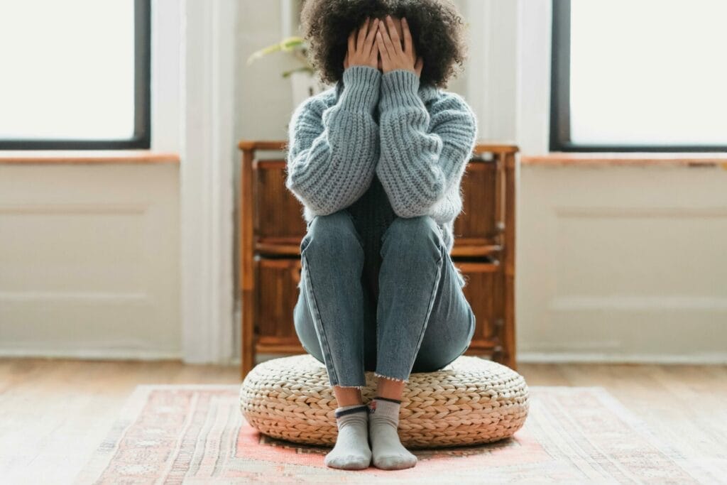 overwhelmed mom sitting on pillow covering her face