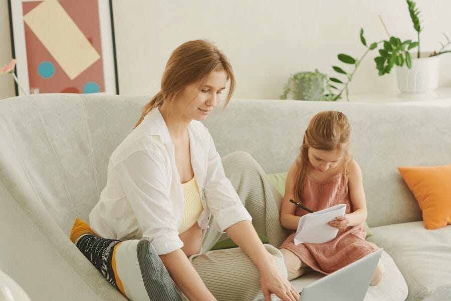 mom and daughter on couch working beside one another