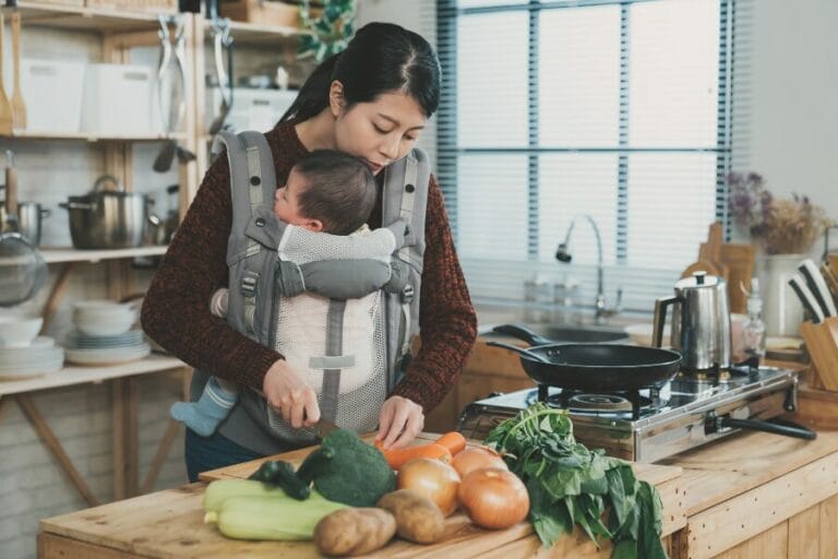 mom prepping dinner with baby in a babycarrier